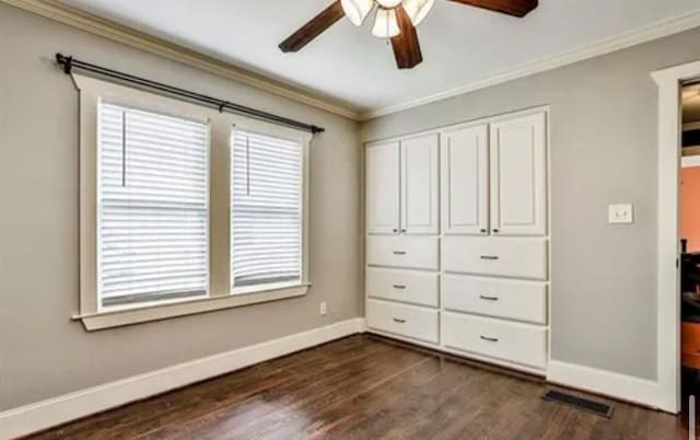 unfurnished bedroom with crown molding, visible vents, dark wood-type flooring, ceiling fan, and baseboards