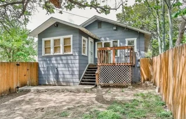 rear view of house featuring a fenced backyard, a wooden deck, and stairs