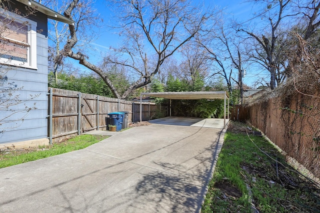 view of car parking with driveway and a fenced backyard