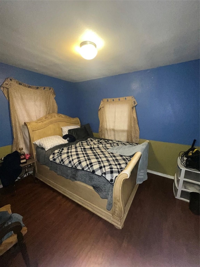 bedroom with dark wood finished floors and baseboards