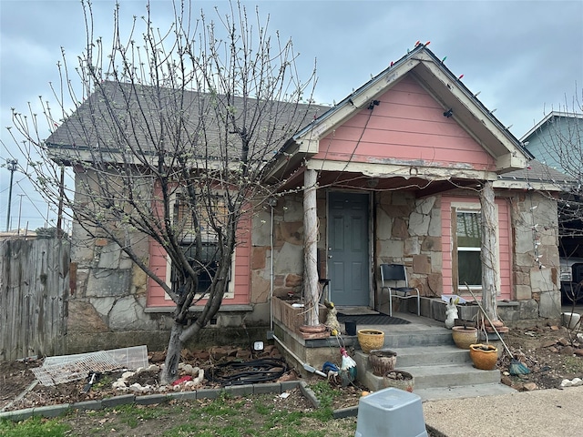 view of front of home with stone siding and fence