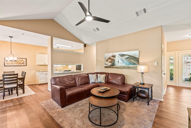 living area with vaulted ceiling, light wood-type flooring, and visible vents