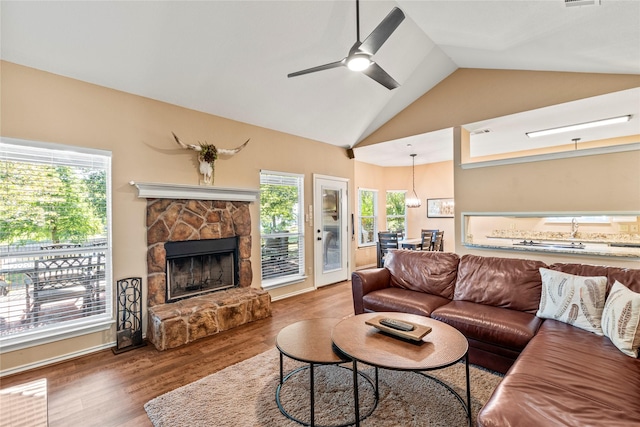 living area featuring lofted ceiling, ceiling fan, dark wood-style flooring, and a fireplace