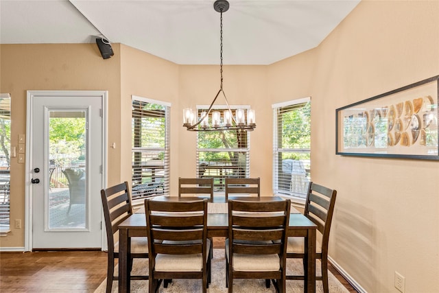 dining area featuring baseboards, wood finished floors, and a notable chandelier