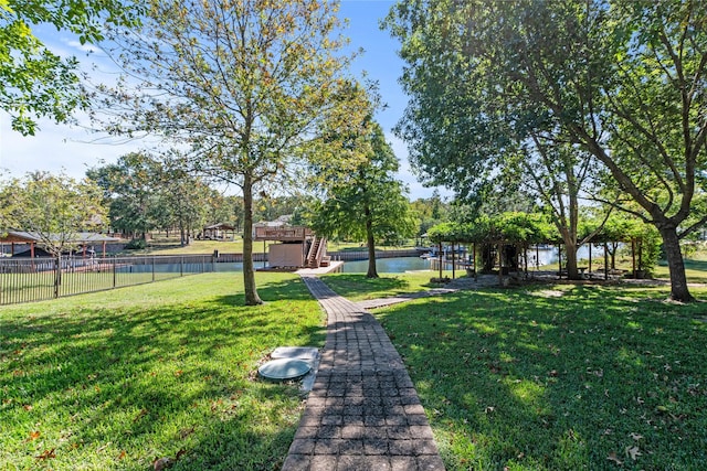 surrounding community with a water view, a lawn, stairway, and fence