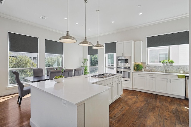 kitchen featuring white cabinets, stainless steel appliances, a kitchen island, and light countertops