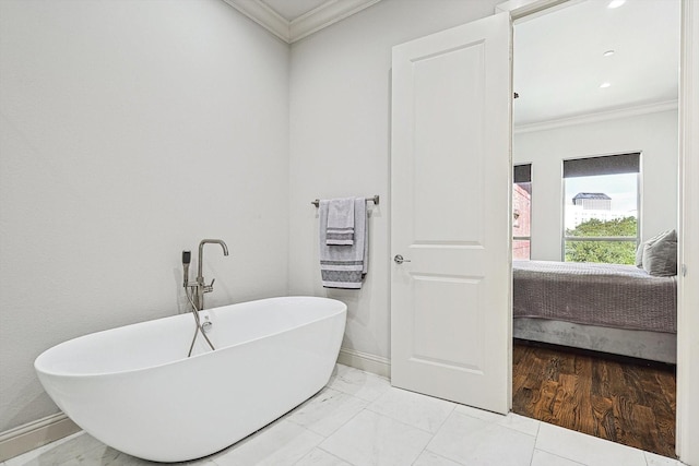 ensuite bathroom with connected bathroom, baseboards, marble finish floor, a soaking tub, and crown molding