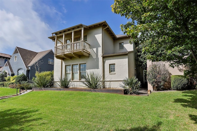 view of front of house with a balcony, brick siding, and a front yard