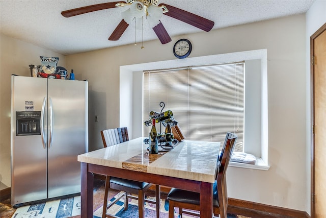 dining area with ceiling fan, a textured ceiling, and baseboards