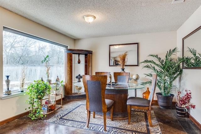 dining area featuring concrete floors, baseboards, and a textured ceiling