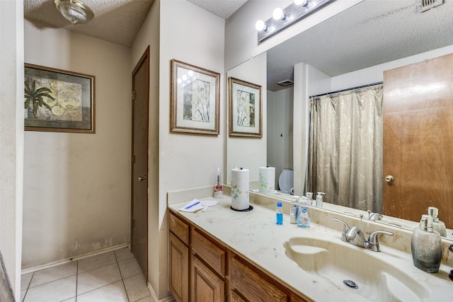 bathroom with tile patterned flooring, baseboards, a textured ceiling, and vanity