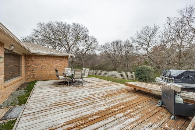 wooden terrace featuring outdoor dining area, area for grilling, and fence