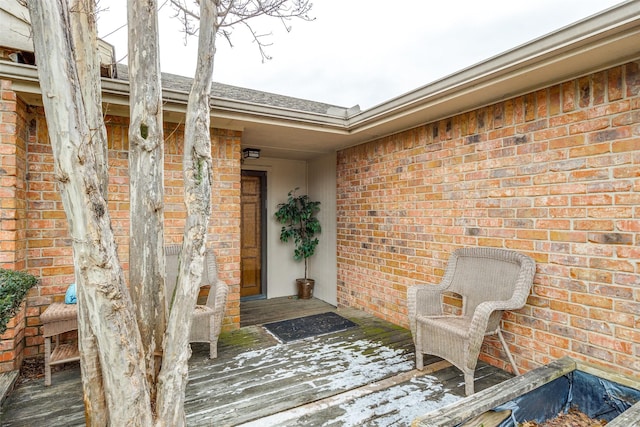 doorway to property featuring brick siding and a wooden deck