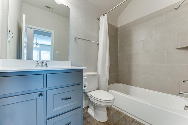 bathroom featuring visible vents, toilet, wood finished floors, shower / bath combo with shower curtain, and vanity