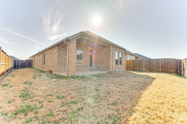 view of side of home featuring a fenced backyard, brick siding, and a patio