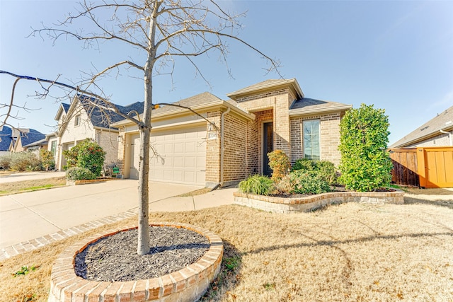 view of front facade featuring a garage, brick siding, driveway, and fence