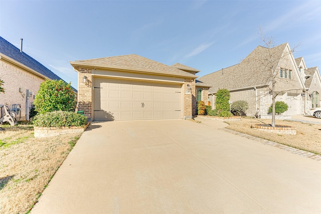 view of front of home with a garage, roof with shingles, concrete driveway, and brick siding