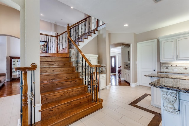 stairs with arched walkways, baseboards, tile patterned floors, and recessed lighting