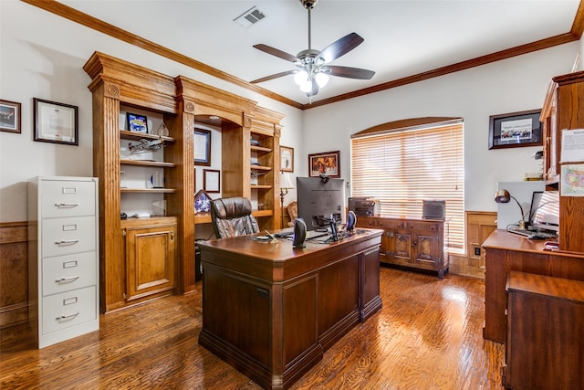 office featuring visible vents, a ceiling fan, wainscoting, dark wood-style floors, and ornamental molding