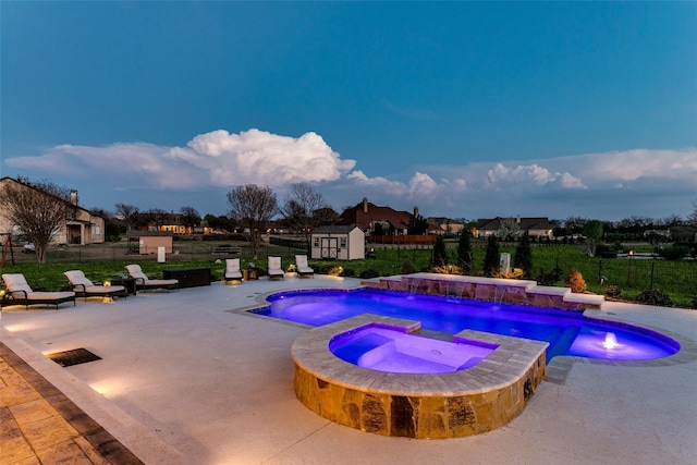 view of swimming pool featuring a fenced backyard, a storage unit, an outdoor structure, a patio area, and a pool with connected hot tub