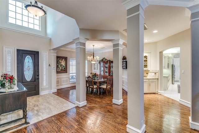 entryway featuring a wealth of natural light, wood finished floors, and decorative columns