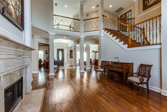 foyer with a healthy amount of sunlight, ornate columns, baseboards, and wood finished floors