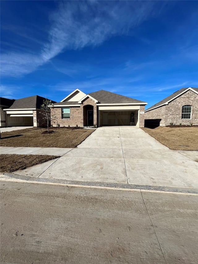 view of front of home with concrete driveway, brick siding, an attached garage, and a shingled roof