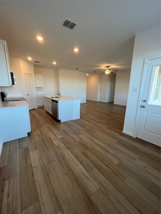 kitchen featuring visible vents, dishwasher, a center island with sink, and white cabinets