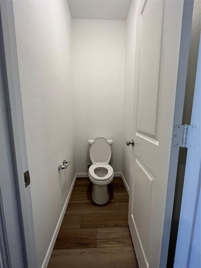 bathroom with wood finished floors, toilet, and baseboards