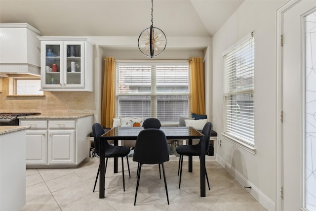 dining area featuring light tile patterned floors, vaulted ceiling, a wealth of natural light, and an inviting chandelier