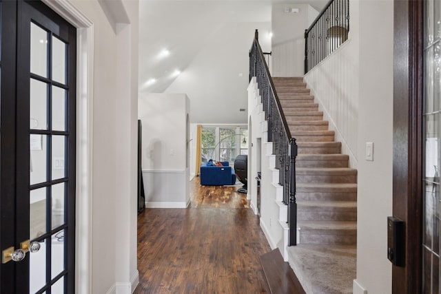 entryway featuring dark wood-style floors, high vaulted ceiling, stairs, and baseboards