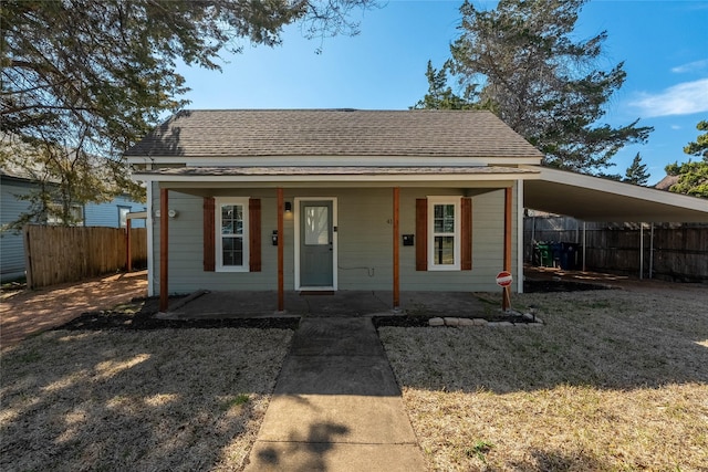 bungalow featuring roof with shingles and fence