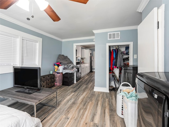 interior space featuring crown molding, visible vents, a ceiling fan, wood finished floors, and washer / dryer