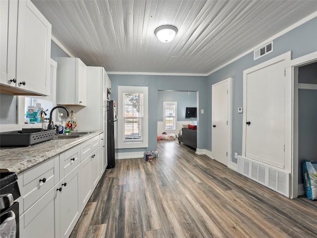 kitchen with light stone counters, a sink, and white cabinetry