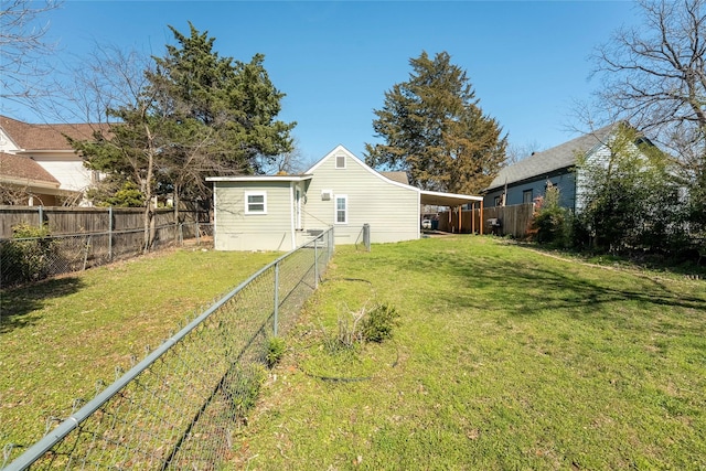 rear view of house with a fenced backyard, a carport, and a yard