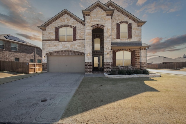 french country home with driveway, an attached garage, fence, a yard, and brick siding