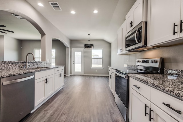 kitchen featuring stone countertops, appliances with stainless steel finishes, white cabinets, and a sink