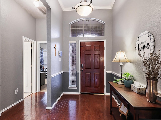 entryway with a textured wall, ornamental molding, wood-type flooring, and baseboards