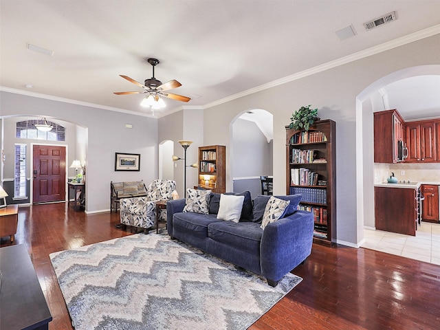 living area with visible vents, dark wood finished floors, and ornamental molding