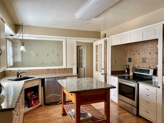 kitchen with light wood-style flooring, appliances with stainless steel finishes, decorative backsplash, and a sink