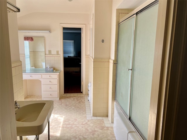 bathroom with a wainscoted wall, shower / bath combination with glass door, tile walls, and tile patterned floors