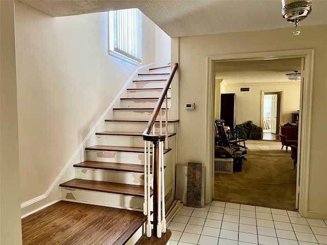 staircase featuring a textured ceiling, plenty of natural light, and tile patterned flooring