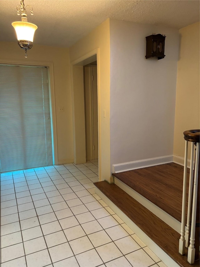 unfurnished room featuring a textured ceiling, baseboards, and light tile patterned floors