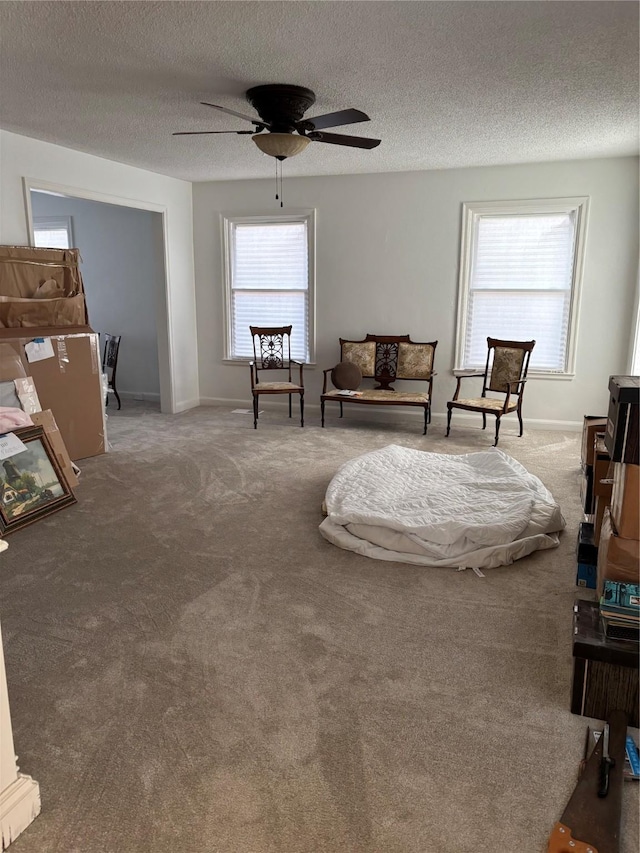 sitting room featuring a textured ceiling, carpet, a ceiling fan, and baseboards