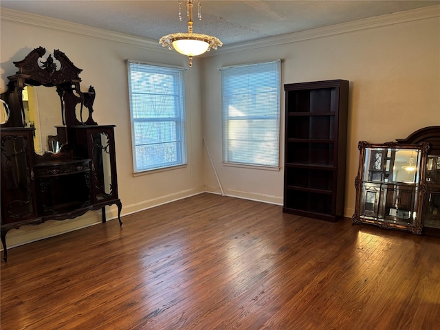 interior space with ornamental molding, a textured ceiling, baseboards, and wood finished floors