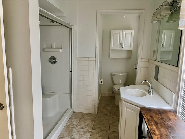 bathroom with tile patterned flooring, a shower stall, toilet, and vanity