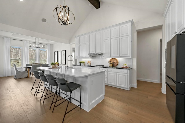 kitchen featuring freestanding refrigerator, a notable chandelier, light wood finished floors, and a sink