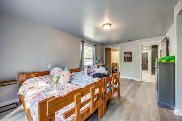 bedroom featuring visible vents, light wood-style flooring, and baseboards