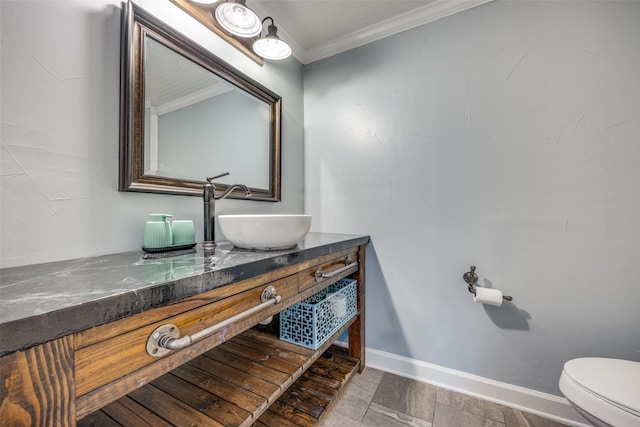 half bathroom featuring toilet, baseboards, crown molding, and vanity