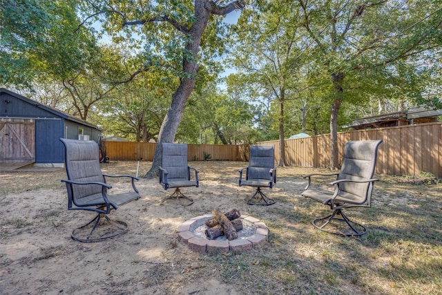 view of yard featuring an outbuilding, a fenced backyard, and a fire pit